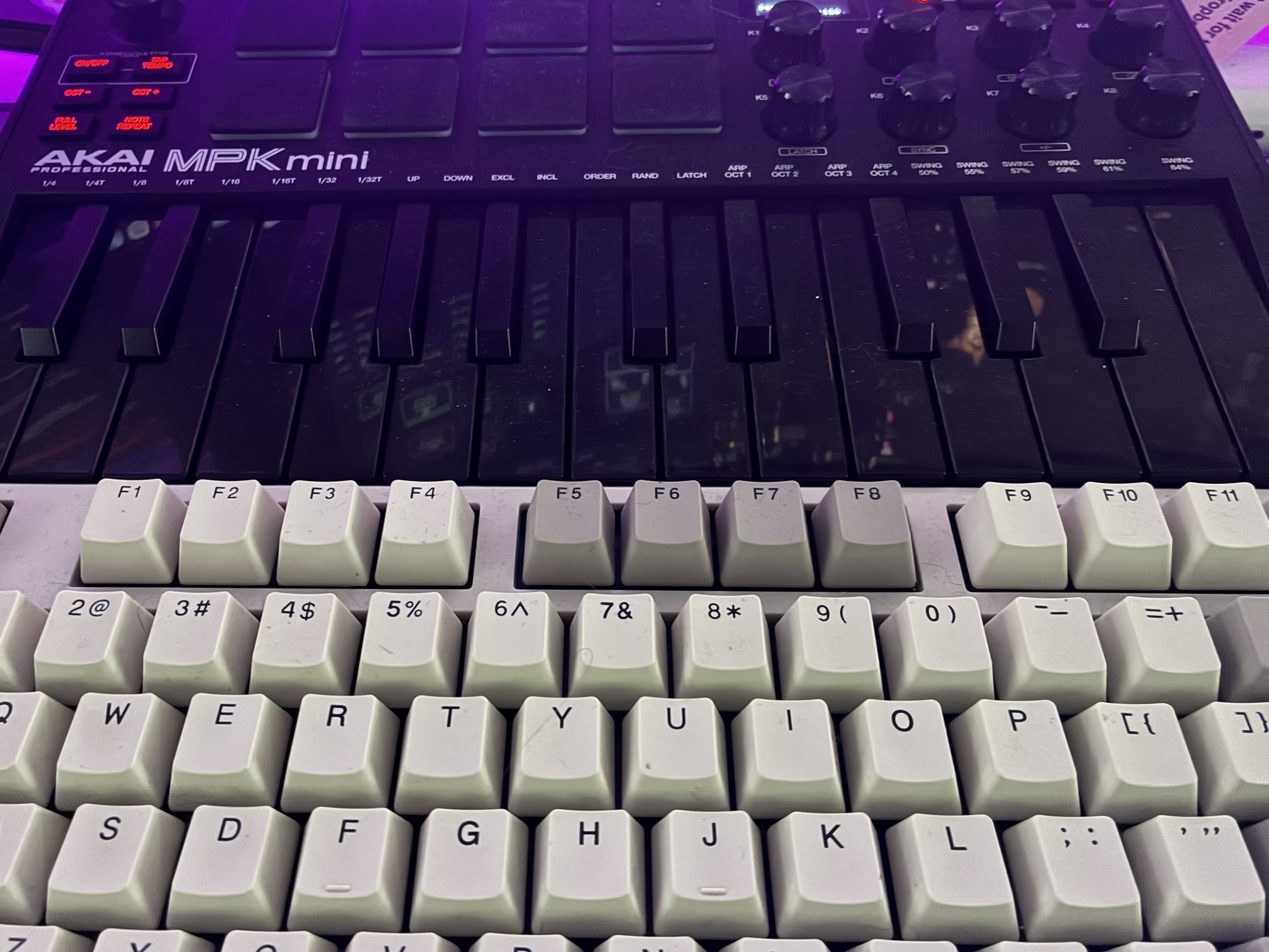 Akai MPK mini sitting on a mechanical keyboard